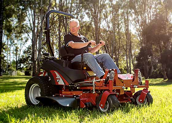 An elderly man mowing grass with a Ferris Mower.