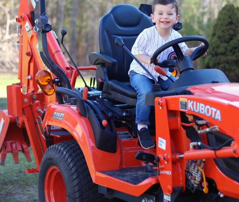 Happy kid atop a Kubota Compact Tractor