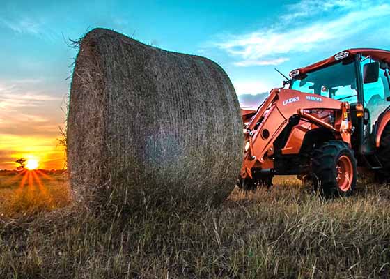 Kubota Tractor in Field with Hay Bale