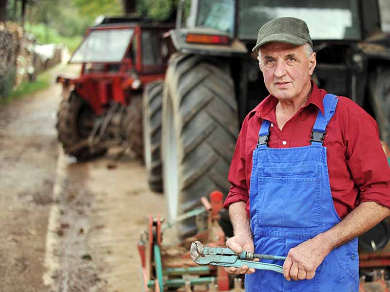 A man with a wrench ready to repair and maintain tractors.