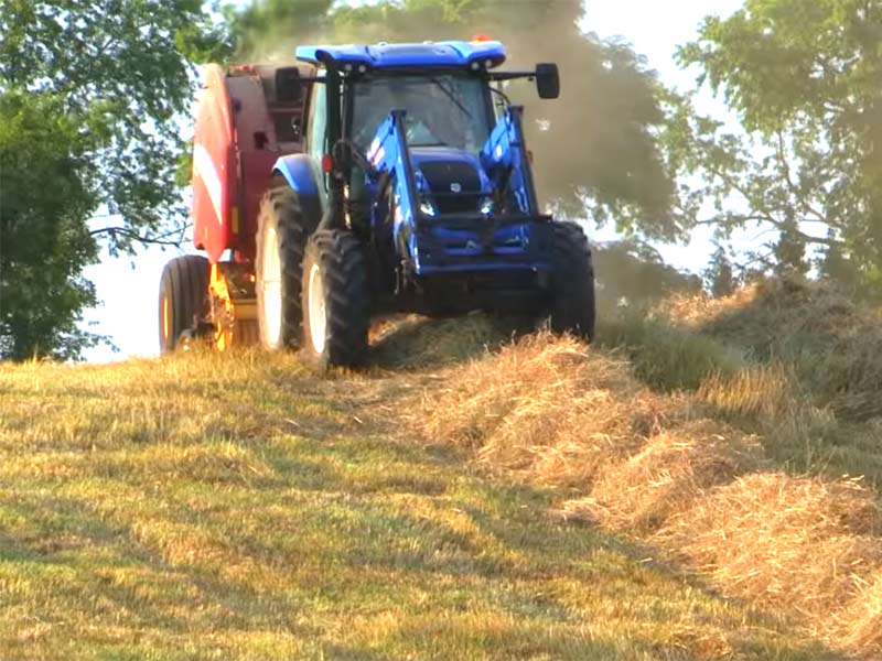 New Holland Roll Belt Round Baler being pulled by New Holland Tractor