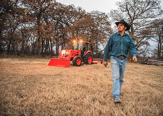 A man walking through field with tractor